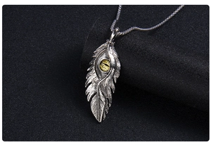 Détail macro du collier pendentif plume gothique en argent avec perle œil maléfique ambre