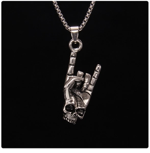 Close-up of gothic stainless steel rock sign pendant with skeleton hand and skull detail