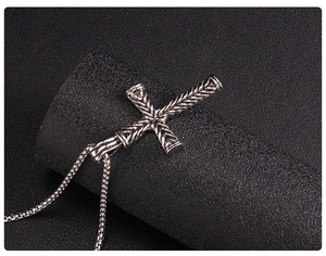 Macro del ciondolo a croce in argento con trama intrecciata e catena box su base nera
