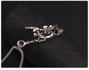 Close-up of punk rock silver skull hand gesture pendant on black leather background