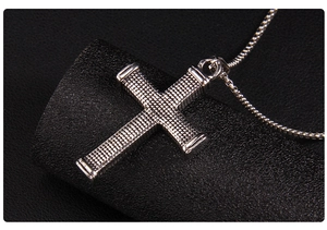 Macro shot of silver stainless steel cross pendant with textured grid pattern detailing