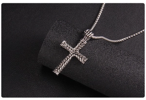 Macro di un ciondolo a croce in argento vintage con trama intrecciata su pelle nera