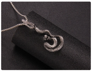 Vue macro d'un pendentif serpent argenté vintage avec écailles sur fond noir mat
