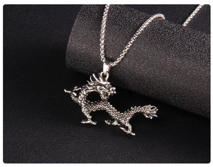 Close-up of silver dragon pendant with box chain on textured black leather