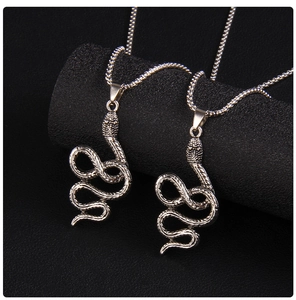 Gros plan de pendentifs serpent argentés avec texture d'écailles et chaînes box en acier