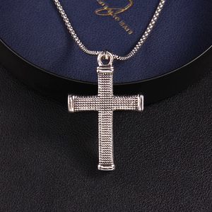 Vintage stainless steel cross necklace with textured pendant on a jewelry gift box