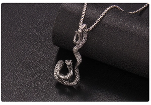 Vue macro du pendentif cobra argenté vintage avec écailles sur fond de cuir noir