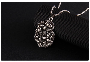 Close-up of gothic stacked skull pendant with vintage silver finish on a box chain