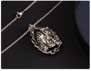 Close-up of vintage Buddha pendant with square box chain on black leather background