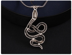 Détail macro d'un pendentif serpent en argent avec dos évidé sur une chaîne fine