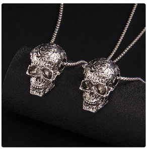Detailed macro view of silver skull pendants featuring intricate gothic vine engravings