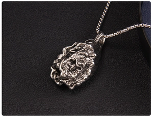 Close-up of vintage silver Buddha and demon pendant on a thick metal box chain