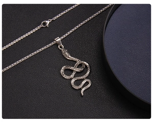 Gros plan détaillé du pendentif serpent avec chaîne argentée sur cuir sombre