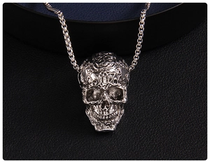 Detailed close-up of retro silver skull pendant featuring intricate relief carvings