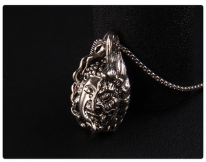 Macro view of Buddha and Demon dual-faced pendant showing detailed silver carving