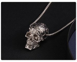 Macro detail of silver vintage skull pendant with intricate engravings and chain