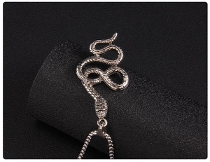 Gros plan d'un pendentif serpent argenté avec écailles détaillées sur chaîne box