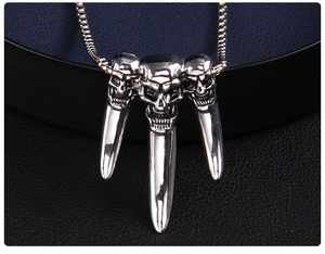 Macro shot of punk style triple skull pendant with long spikes and vintage silver finish