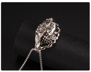 Detail of vintage silver Buddha and demon pendant necklace with intricate carvings