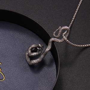 Collier avec pendentif serpent en argent rétro et écailles sur fond noir texturé