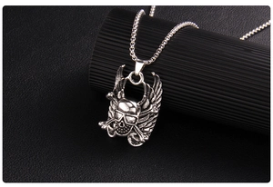 Detail of punk silver skull pendant with wings and crossbones on vintage square chain