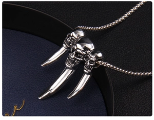 Macro shot of three punk silver skull heads pendant on a steel chain necklace