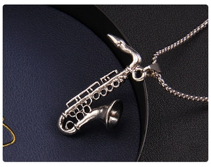 Detailed macro view of a silver saxophone pendant with a metallic beaded chain