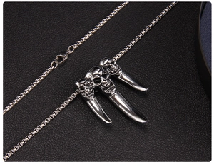 Macro detail of punk three-skull and claw pendant with polished steel bead chain