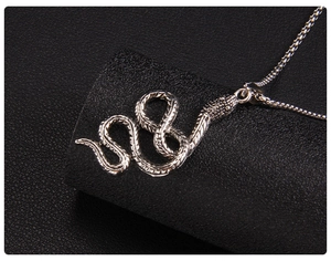 Gros plan d'un pendentif serpent argenté avec écailles détaillées sur fond de cuir noir