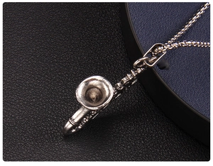 Macro shot of silver saxophone pendant with detailed metal texture on a box chain
