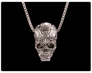 Detailed macro of a punk skull pendant with intricate vintage textures on black background
