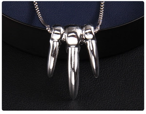 Macro detail of silver punk necklace featuring three sharp claw pendants on a snake chain