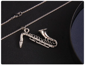 Macro view of vintage silver saxophone pendant with detailed carving on black leather