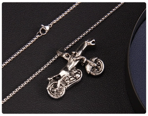 Macro shot of silver retro motorcycle necklace with vintage finish on black leather background