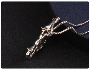 Close-up of a vintage silver motorcycle pendant with chain on black leather background