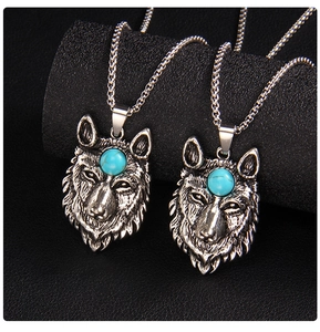 Close-up of a silver wolf head pendant with blue stone inlay on a bead chain necklace