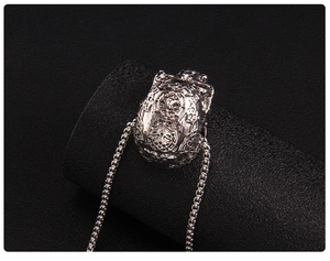 Detailed close-up of a hollow carved skull pendant with a silver square box chain necklace