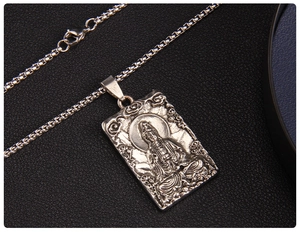 Dettaglio macro del ciondolo vintage Guanyin con rilievo su catena a maglia quadrata