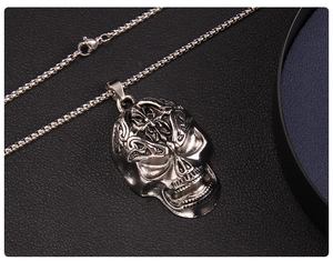 Detail of gothic silver skull pendant with cross engraving on black leather background