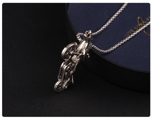 Detailed close-up of a vintage silver motorcycle pendant with an intricate box chain