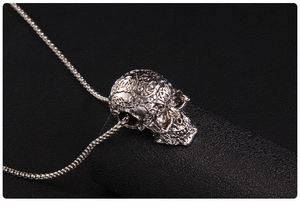 Macro detail of silver skull pendant with intricate Baroque engravings and box chain