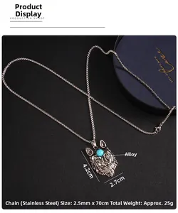 Detailed close-up of a vintage wolf head pendant with a blue bead on a black surface