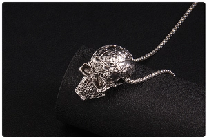 Macro shot of antique silver skull pendant with detailed engraving and ball chain