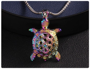Macro shot of colorful iridescent sea turtle pendant with hollow coin pattern on blue base
