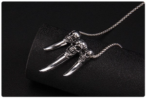 Macro shot of three stainless steel skulls with long tusk pendants on a punk bead chain