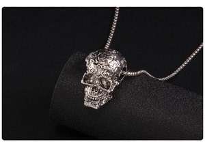Macro detail of gothic skull pendant with intricate silver engravings on a black stand