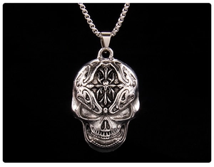 Detailed view of silver skull pendant with intricate totem carvings and square link chain
