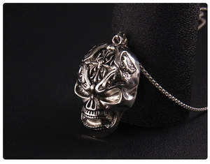 Macro shot of vintage punk skull necklace with cross engraving and aged silver finish