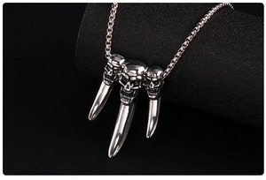 Detailed view of punk necklace featuring three skulls with sharp metal claw pendants
