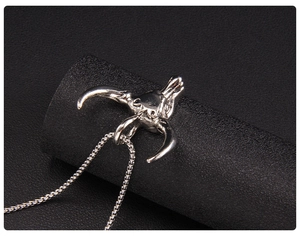Gros plan d'un pendentif tête de taureau argenté vintage sur fond texturé noir